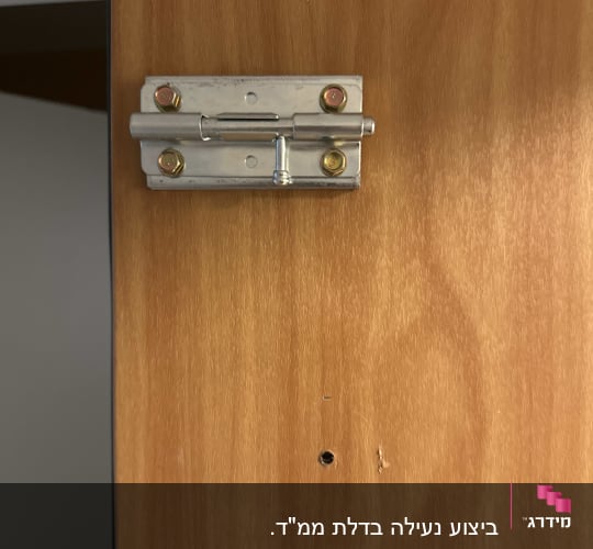 בריח מתכת מותקן על דלת עץ